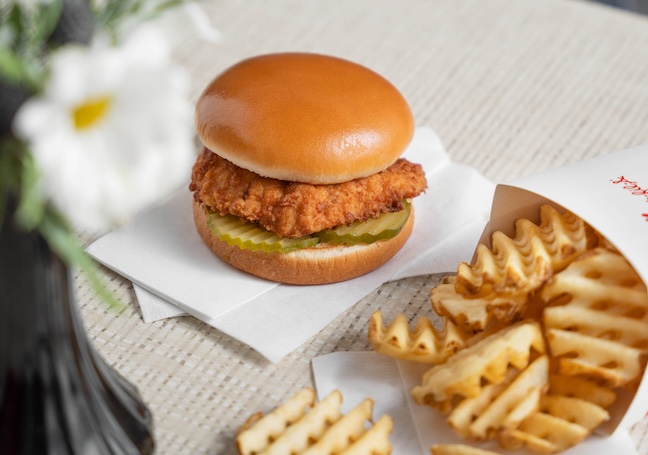 Chick-fil-A® Chicken Sandwich on white napkins next to Waffle Fries